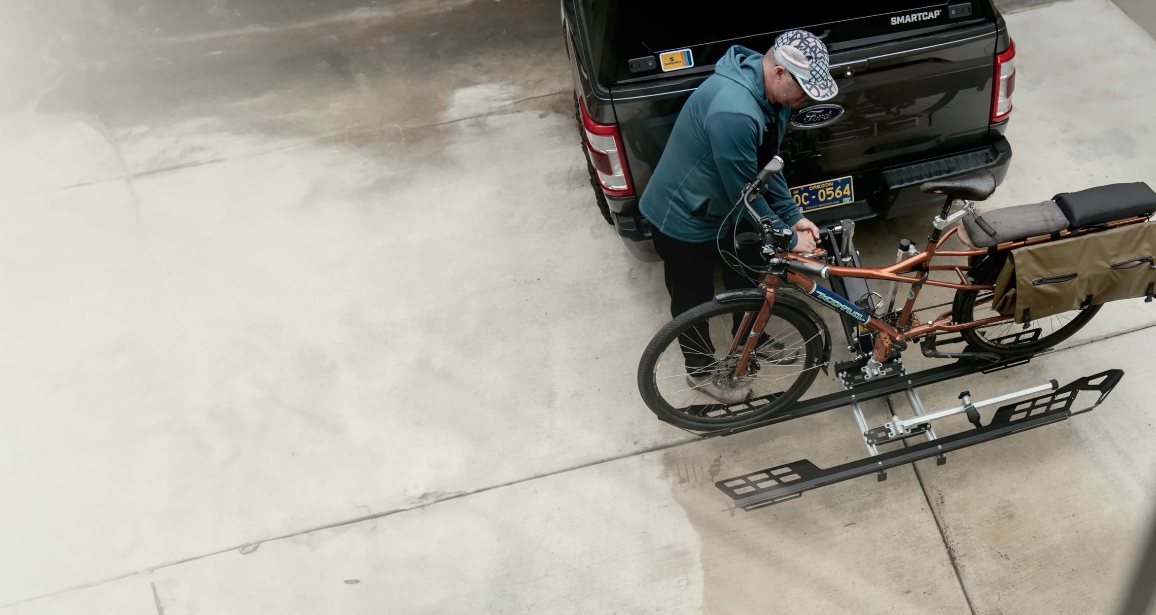 Man loading long bike into The Lifter rack, positioned on the ground